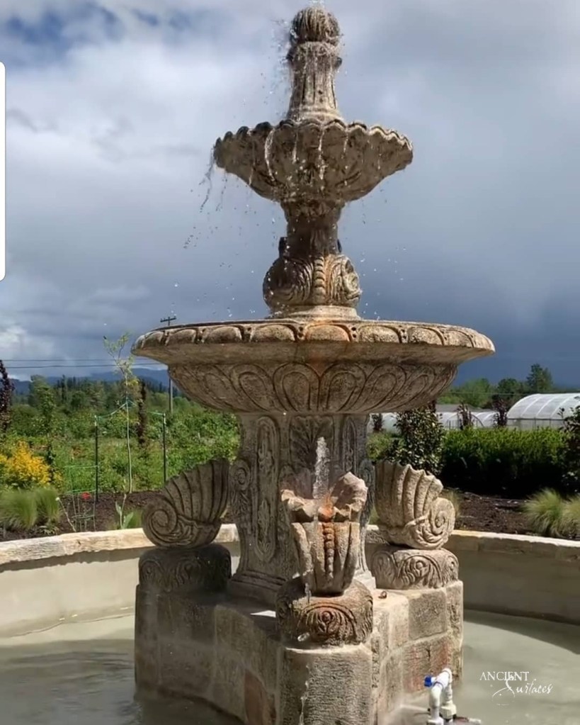 An antique limestone pool fountain by Ancient Surfaces, adding a touch of Mediterranean elegance to an outdoor space.