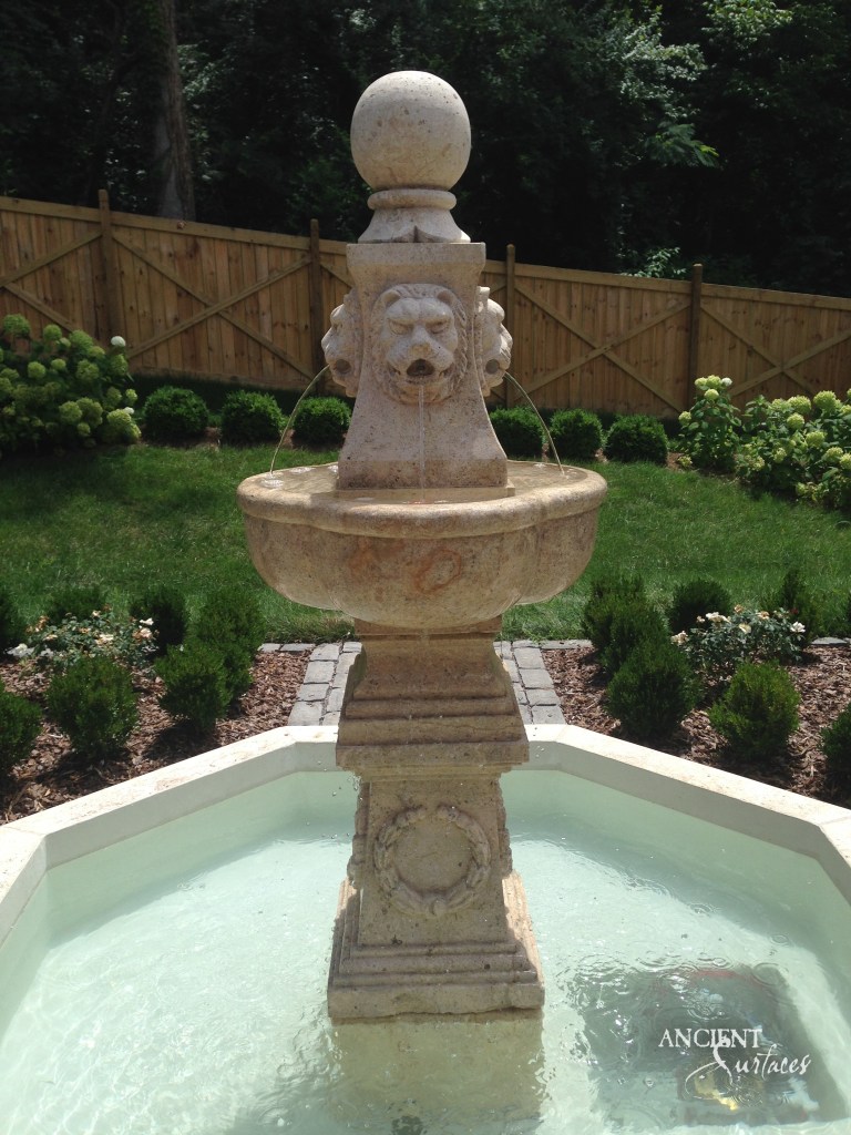 antique limestone pool fountain by Ancient Surfaces, its robust form and warm tones transforming a pool area into a Mediterranean oasis